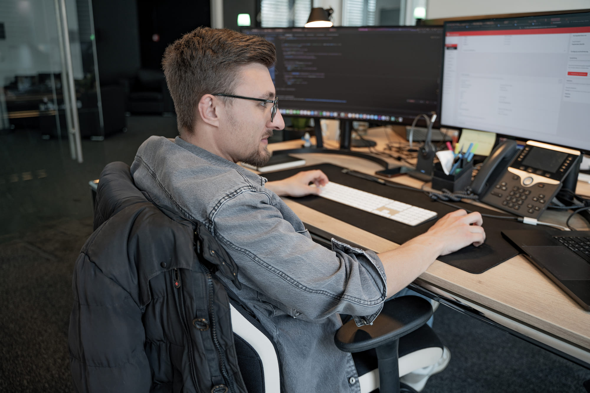 Pascal aus dem Team von digitalbynature am Arbeitsplatz mit Code auf zwei Monitoren im Büro in Heppendorf